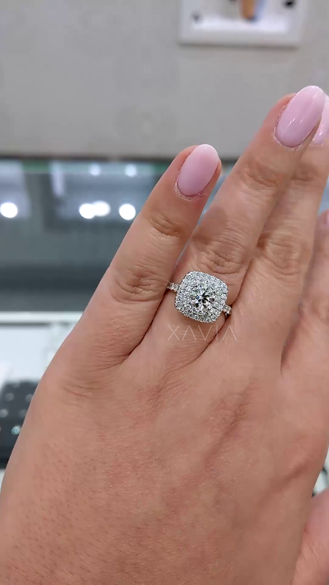 hand shot of double halo lab grown diamond engagement ring with cushion outline and slim pavé band reflecting luxury bridal styling