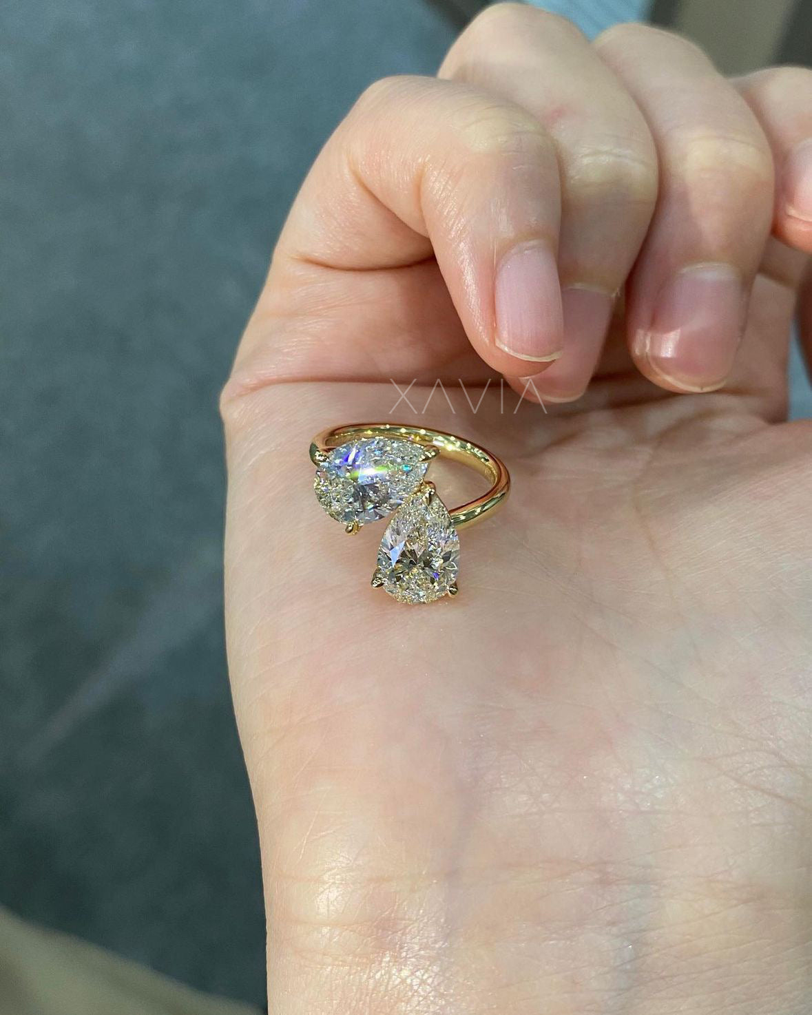 handheld image of pear cut toi et moi diamond ring in high-polish gold