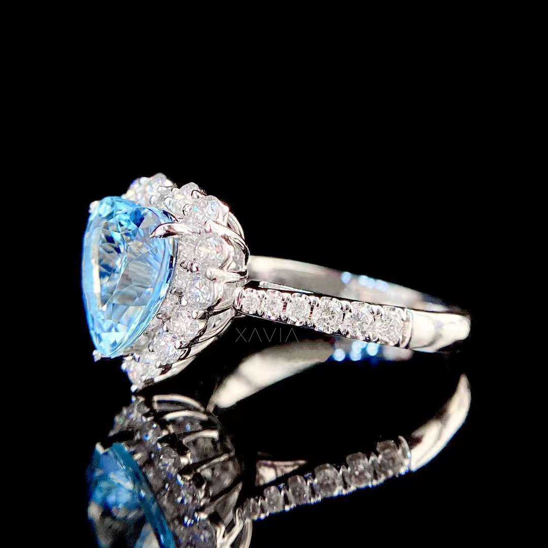 Detailed side view of diamond pavé band and heart cut blue gemstone halo center stone set in polished white gold engagement ring
