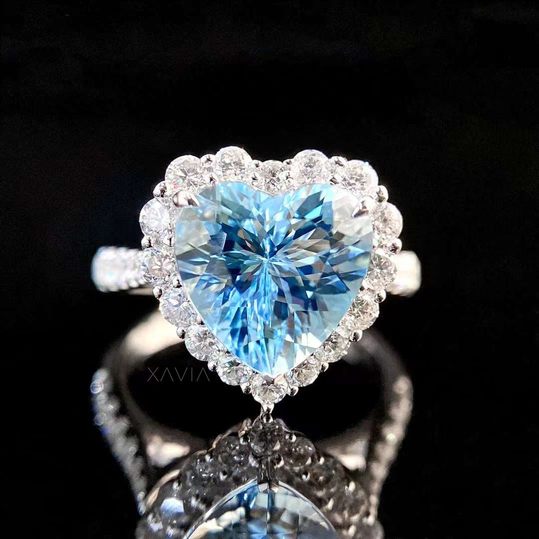 Macro top view of heart cut ocean blue gemstone surrounded by brilliant round lab diamond halo emphasizing fire and brilliance in engagement ring