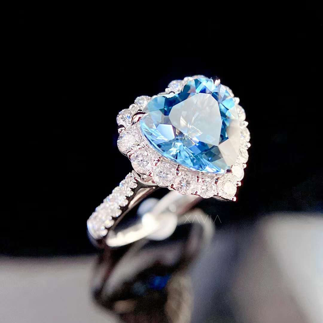 Angled macro view of heart shaped blue gemstone halo ring highlighting round brilliant diamond halo and elegant pavé diamond band