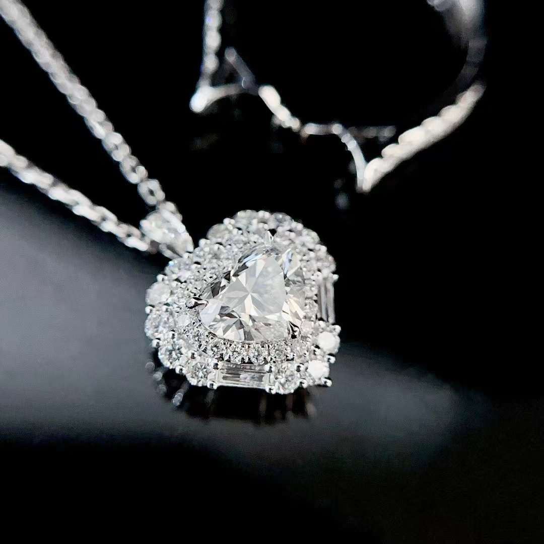 Detailed close up of heart shaped diamond pendant featuring double halo diamonds and brilliant center stone set in polished white metal