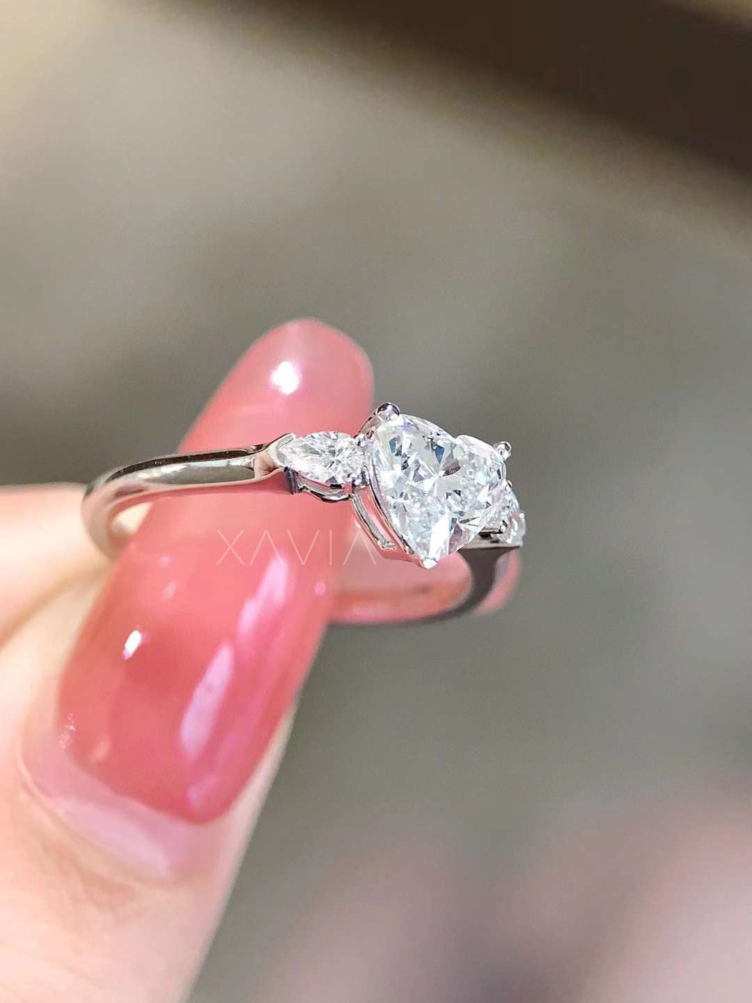 Side angle of heart shaped lab grown diamond three stone engagement ring with pear side diamonds and elegant prong setting on slim high polish band