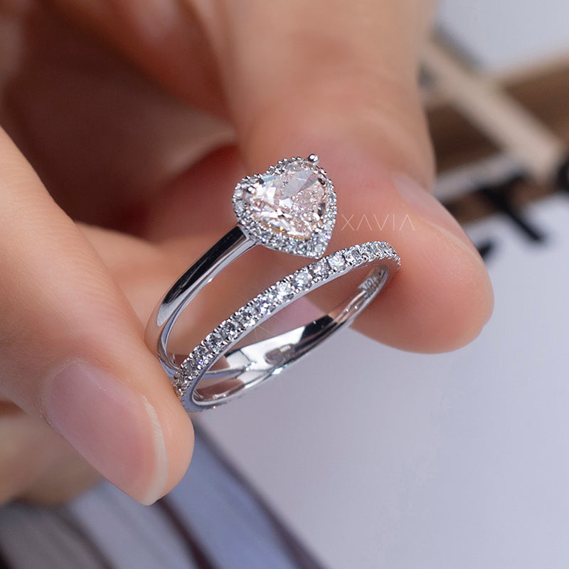 close-up of heart cut lab diamond halo engagement ring with eternity band in white gold worn on model’s hand