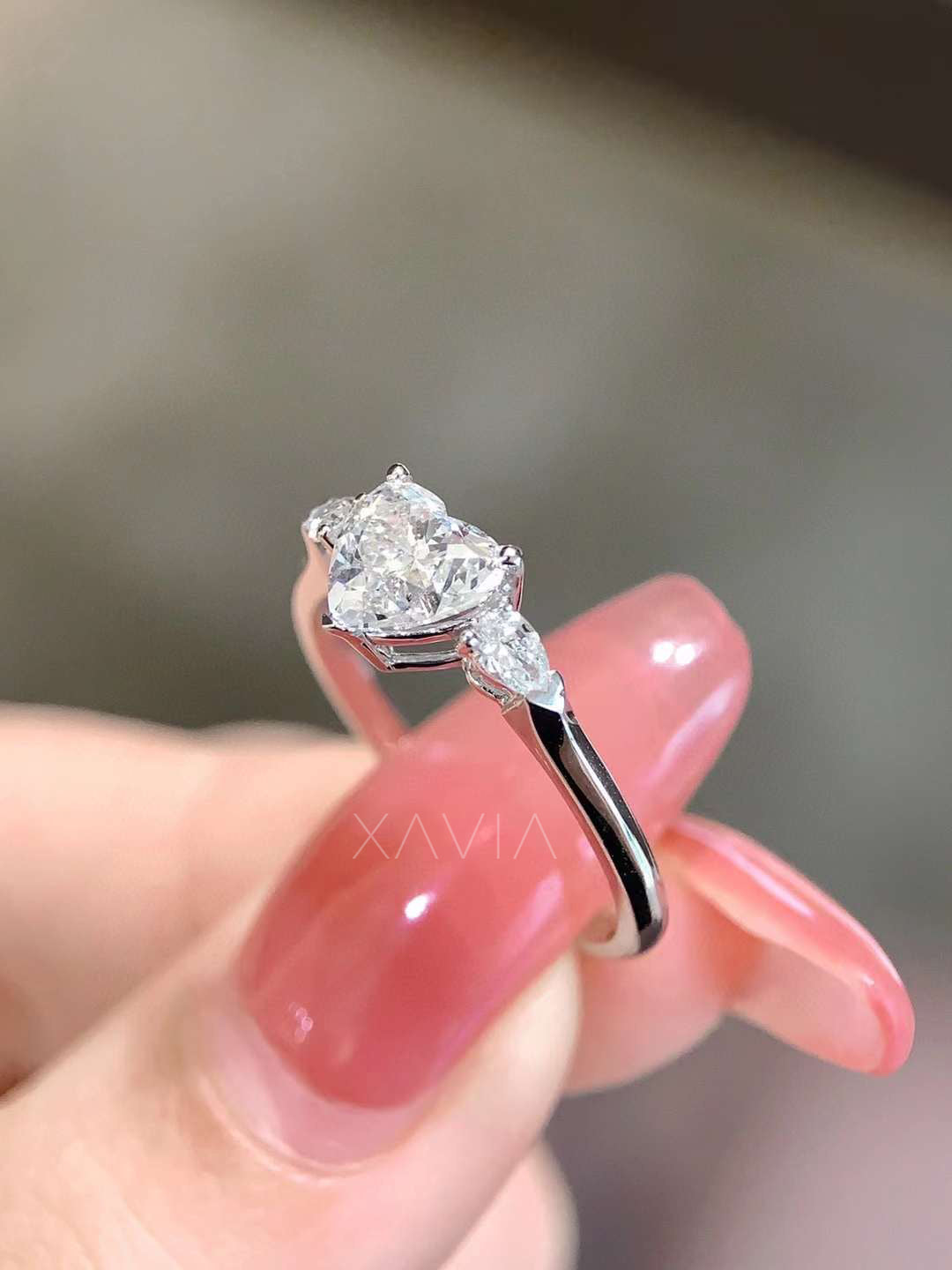 Profile view of heart cut lab grown diamond engagement ring showing raised prong setting and pear shaped side diamonds with sleek polished metal band