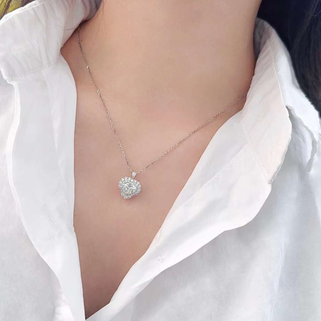 Heart shaped diamond halo pendant necklace worn by model showing brilliant center diamond surrounded by round halo stones on delicate white gold chain