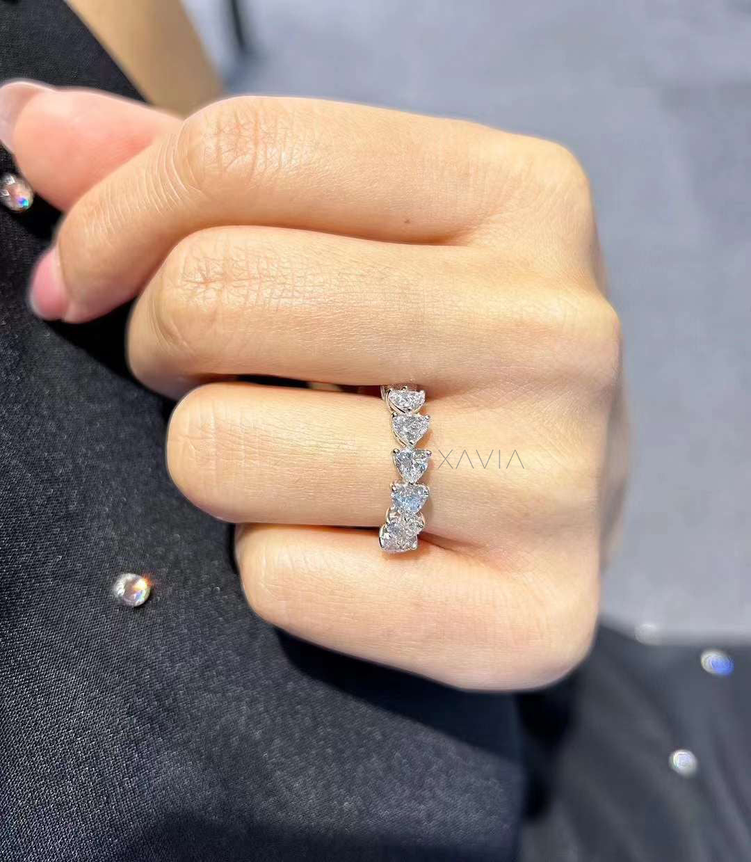 Heart-shaped diamond half eternity ring worn on finger, styled with glossy nails and black dress