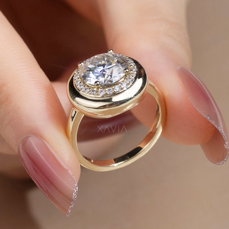 hand holding yellow gold domed bezel halo diamond ring with round brilliant lab diamond center and pavé halo