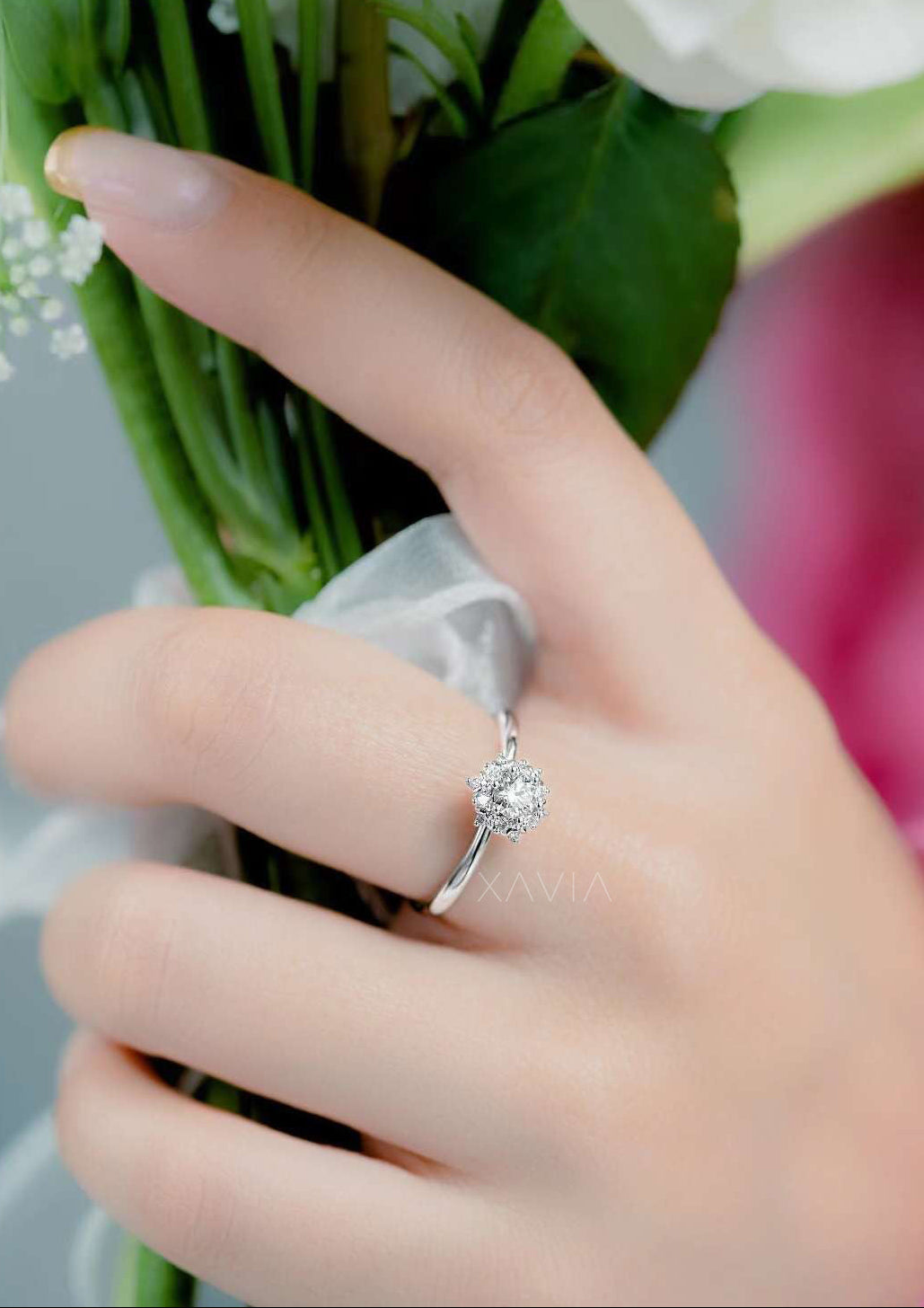 Hand wearing a silver ring with a diamond, holding a bouquet of flowers.