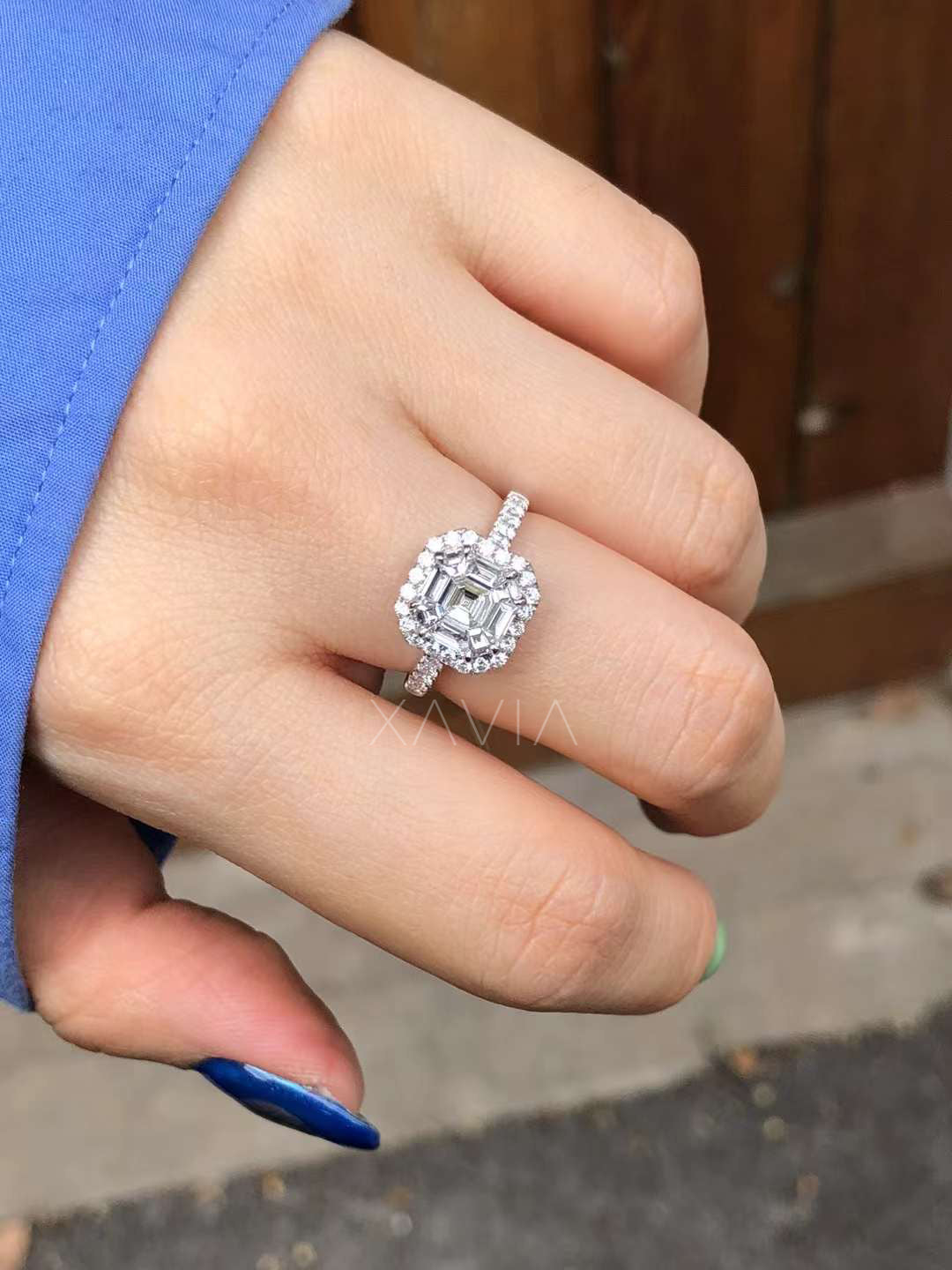 closeup of asscher cut lab diamond engagement ring on hand showing layered halo design and pavé band sparkle in natural lighting