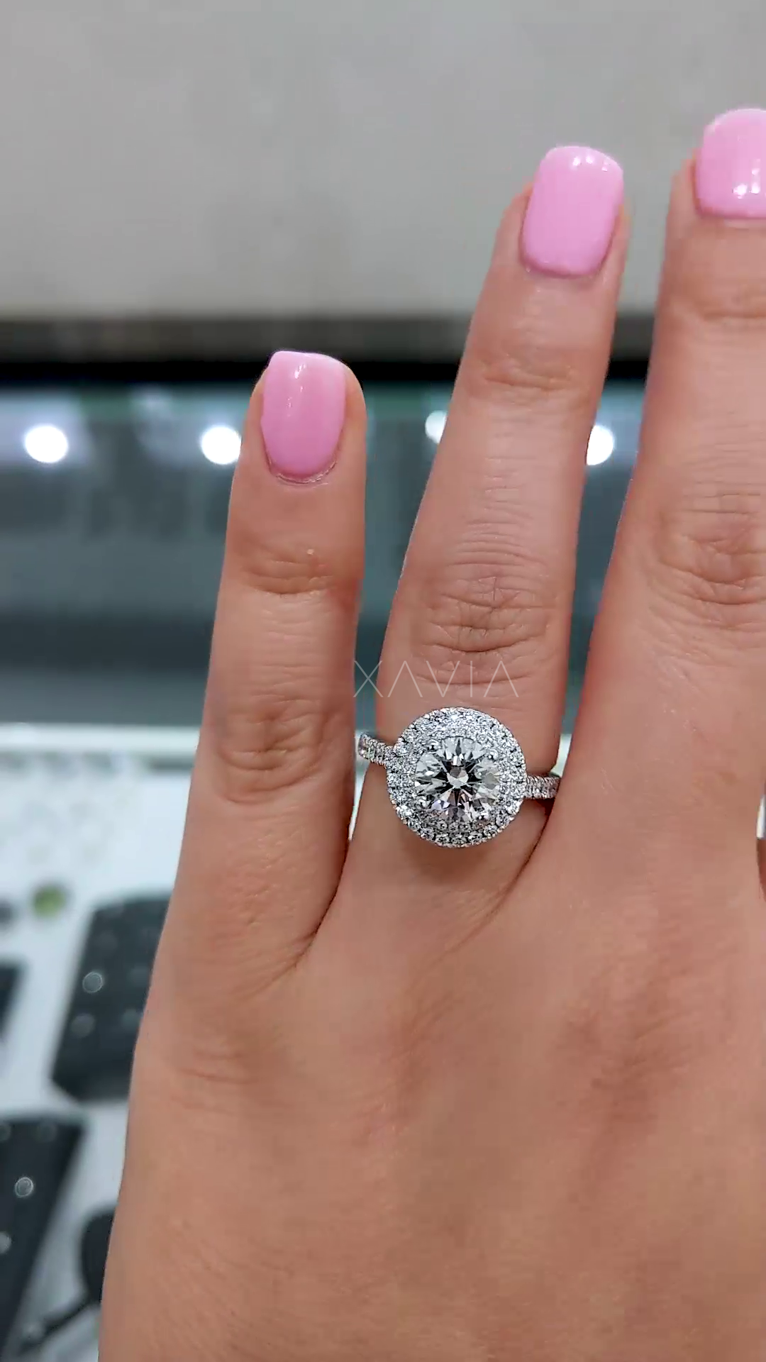 front angle view of round diamond engagement ring with dual halo setting and slim pavé band highlighting brilliance and layered halo design