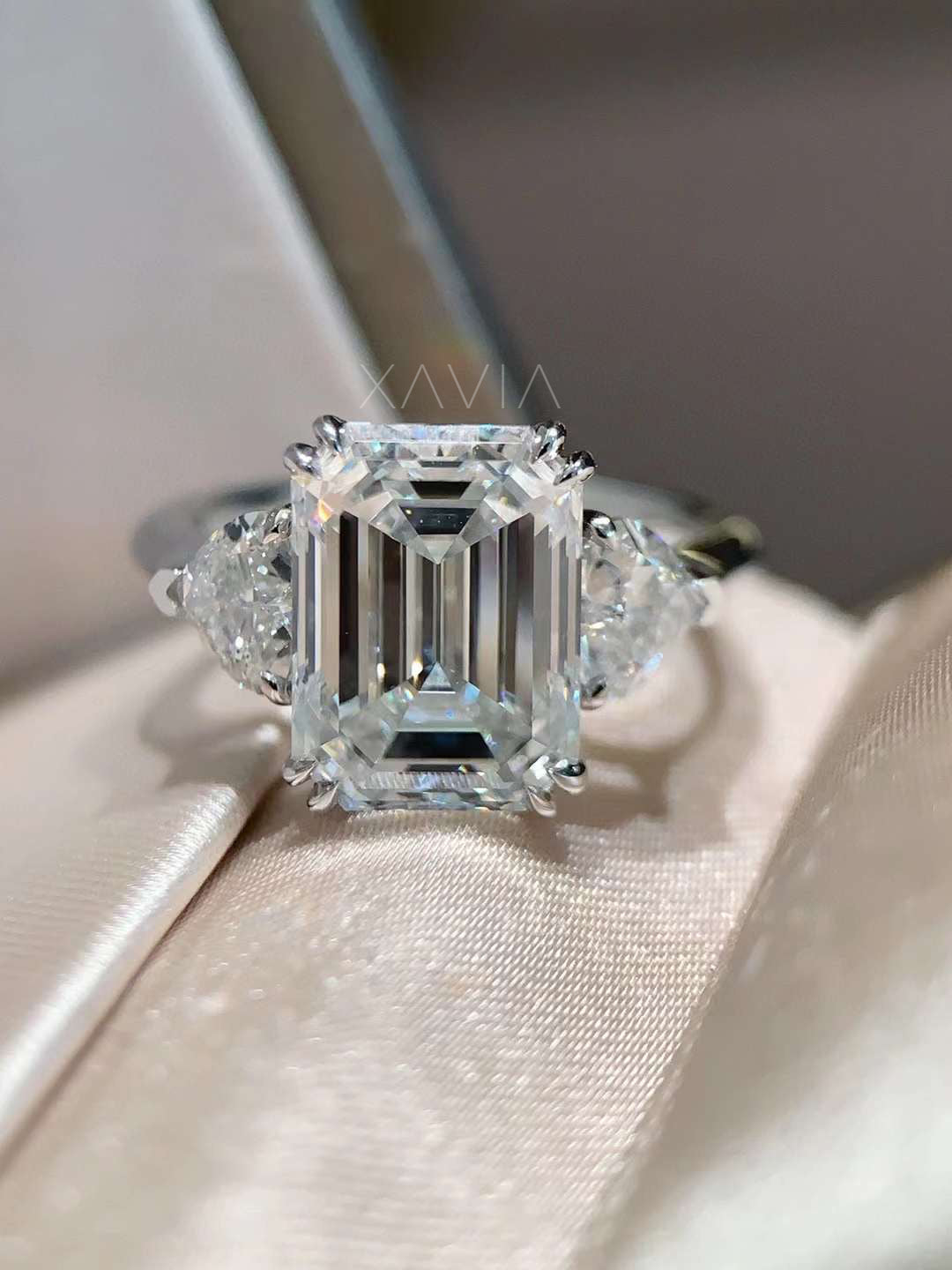 luxury emerald cut lab diamond engagement ring photographed on silk background highlighting step cut brilliance and trillion side diamonds
