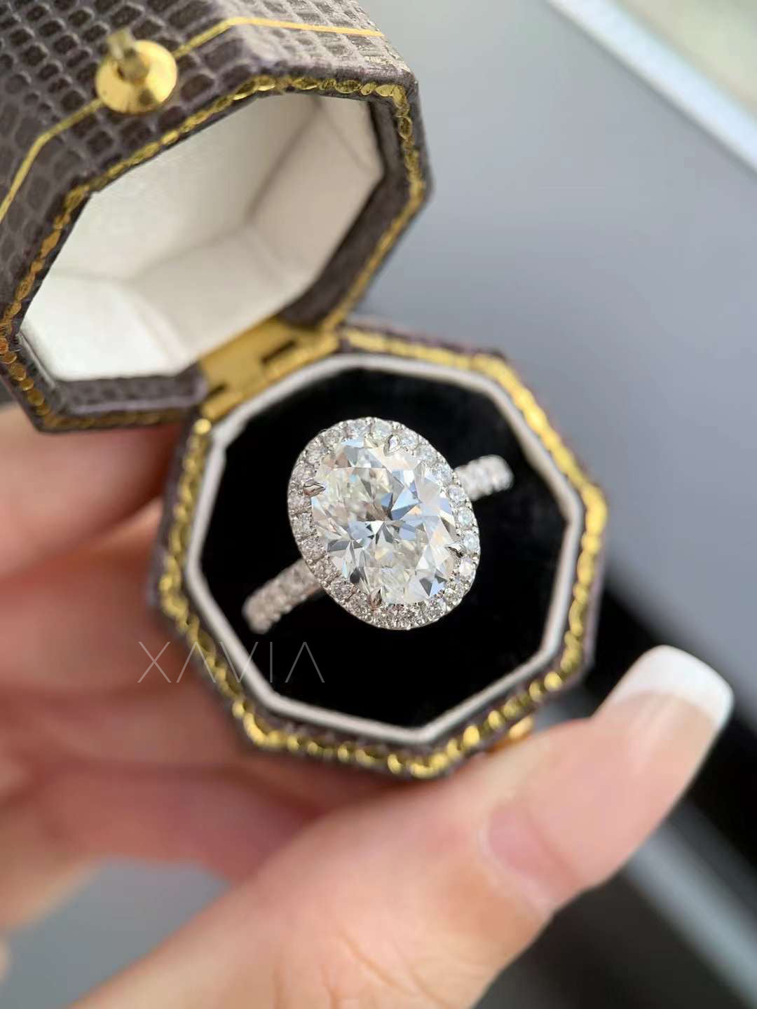 Luxury close-up of oval cut halo engagement ring with brilliant pavé band, shown inside elegant octagon ring box
