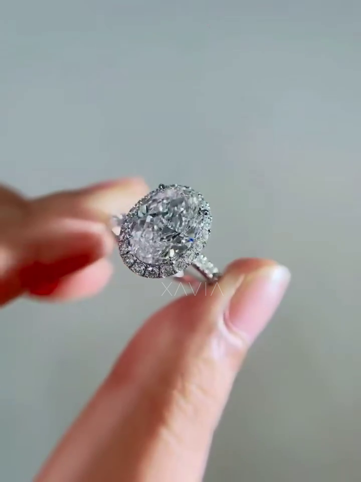 luxury oval lab grown diamond halo engagement ring held in hand showing center oval diamond, halo setting and pavé diamond shank