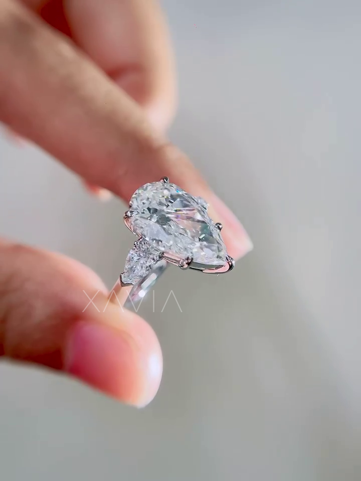 luxury pear cut lab grown diamond engagement ring close up highlighting brilliant center stone and symmetrical trillion side diamonds