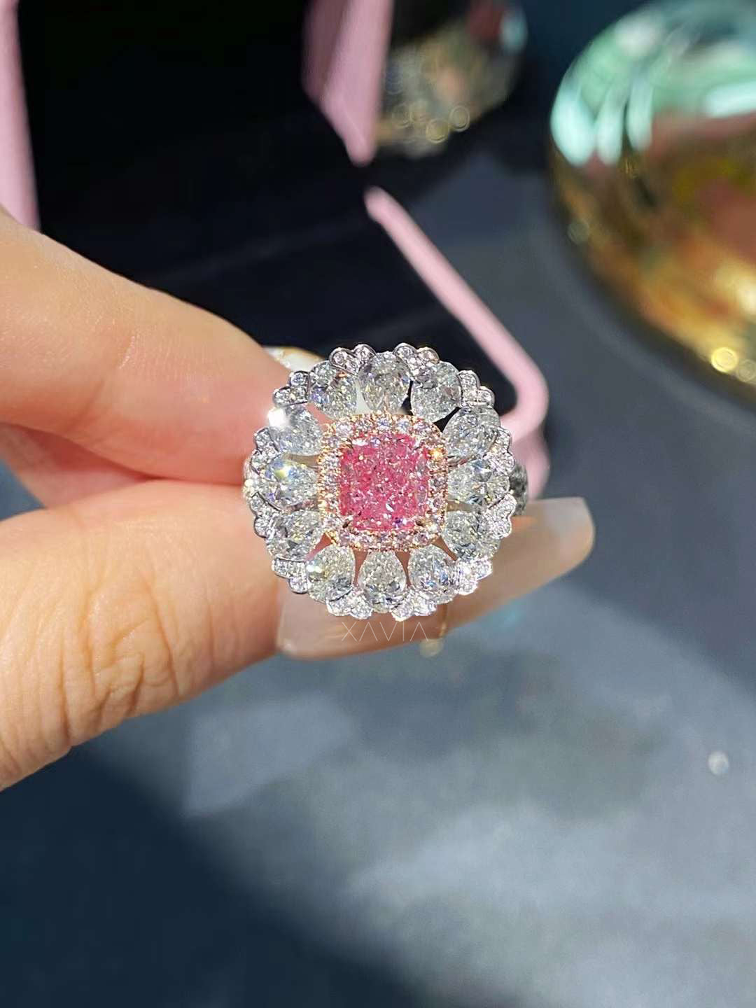cushion pink lab diamond surrounded by floral halo of pear and round diamonds held in hand