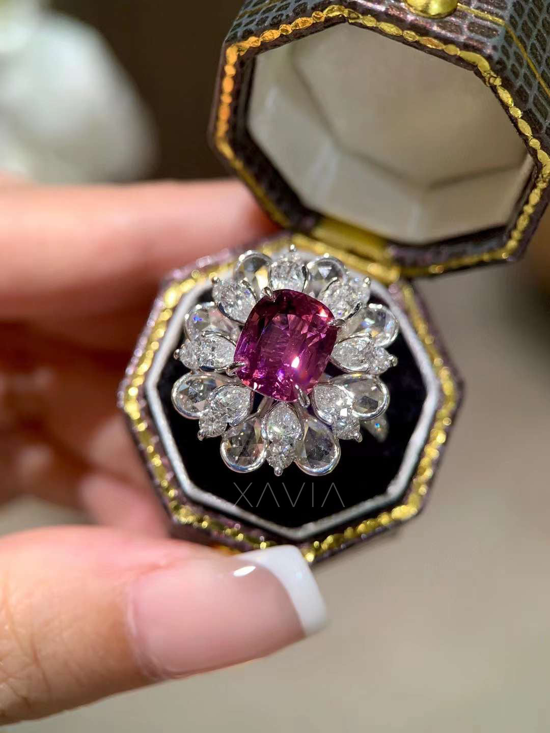 Detailed close up of cushion cut pink lab grown diamond ring surrounded by pear shaped halo diamonds arranged like flower petals in bright white metal setting