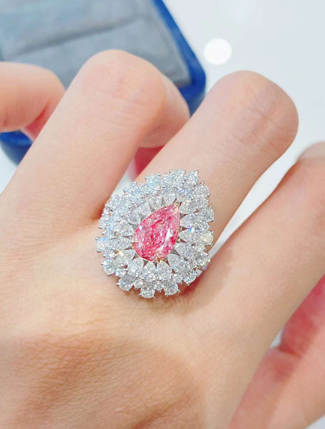 Luxury pear cut pink lab diamond engagement ring worn on finger with marquise halo design emphasizing bold sparkle and refined white gold band