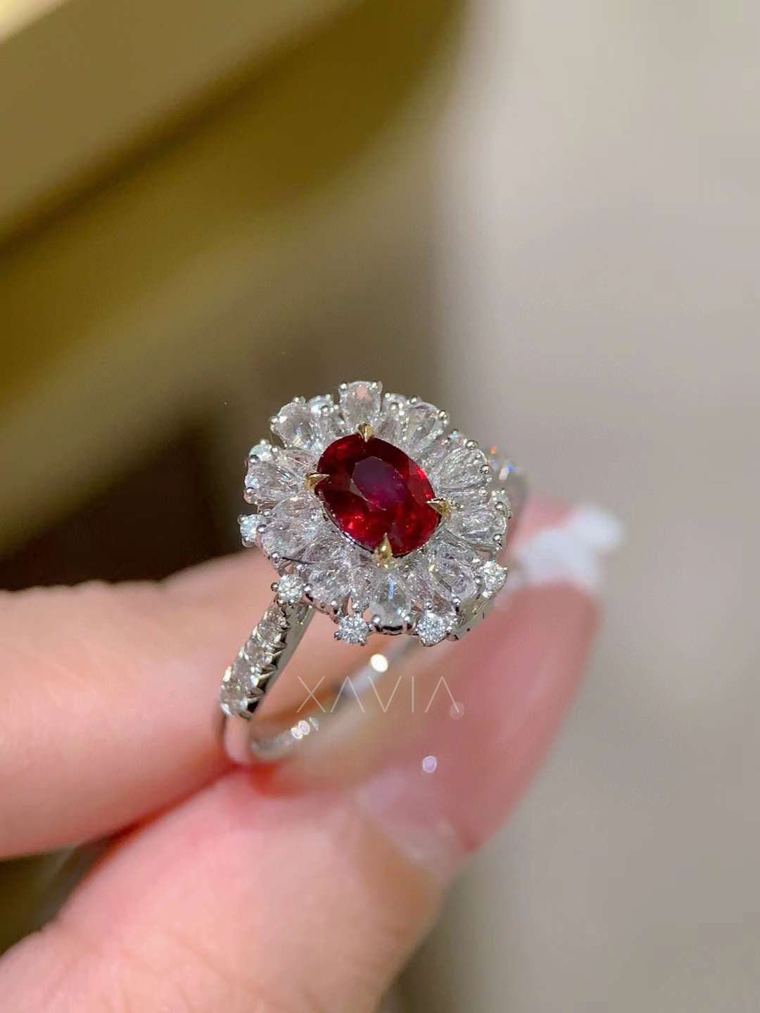 Angled perspective of oval red gemstone halo ring with radiant marquise diamond cluster halo and pavé diamond band highlighting sparkle and setting craftsmanship