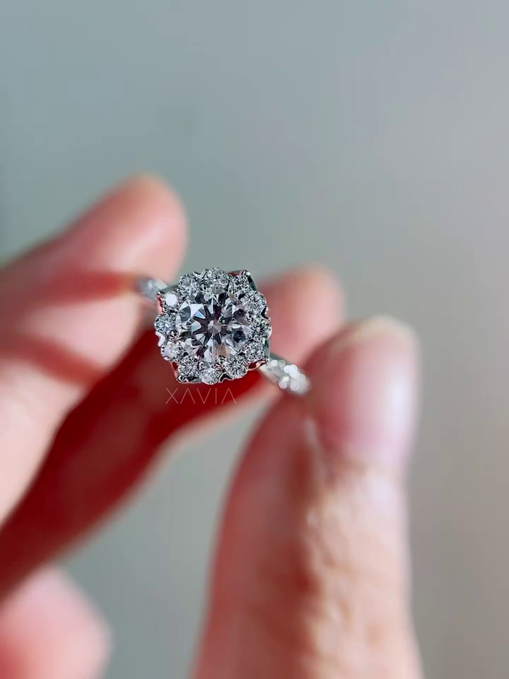 Detailed macro view of round brilliant center diamond surrounded by sparkling round halo diamonds with slim pavé engagement band