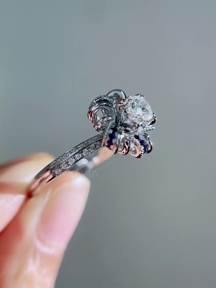 Angled luxury engagement ring with round brilliant lab diamond center framed by sculptural sapphire floral halo and pavé band