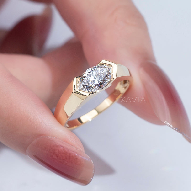close-up of marquise cut lab-grown diamond engagement ring in yellow gold bezel setting shown on model’s hand
