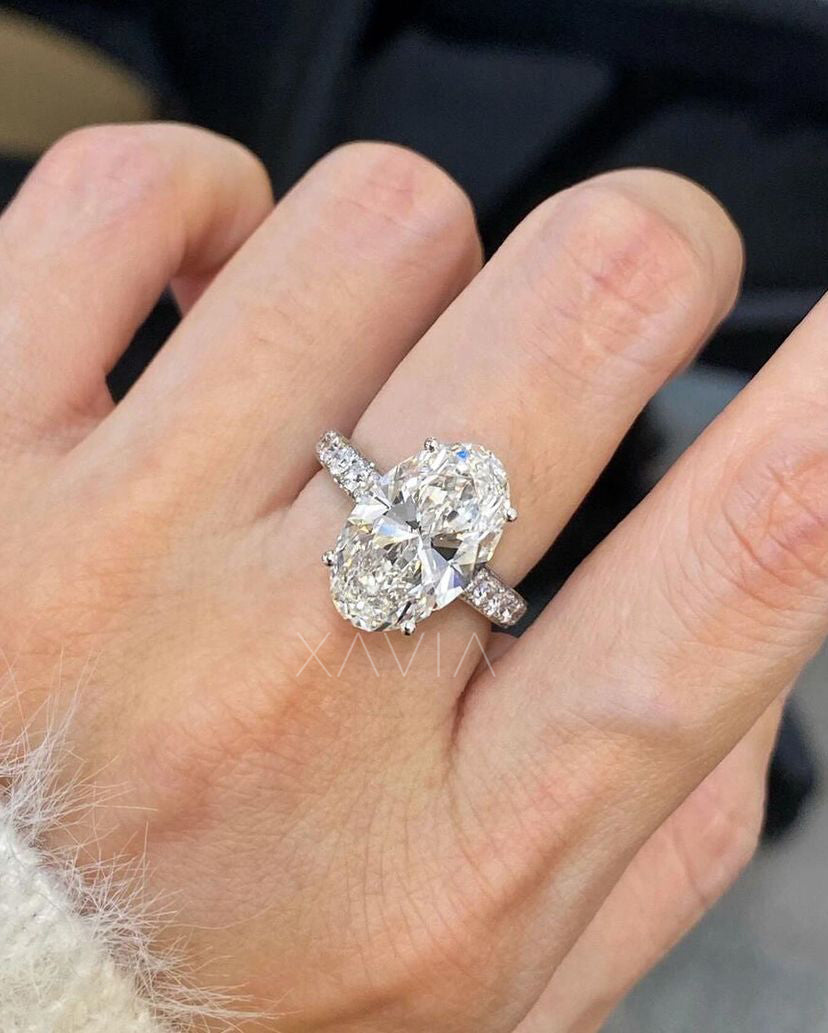 Model wearing elongated oval cut lab diamond engagement ring with pavé diamond shank in platinum style band