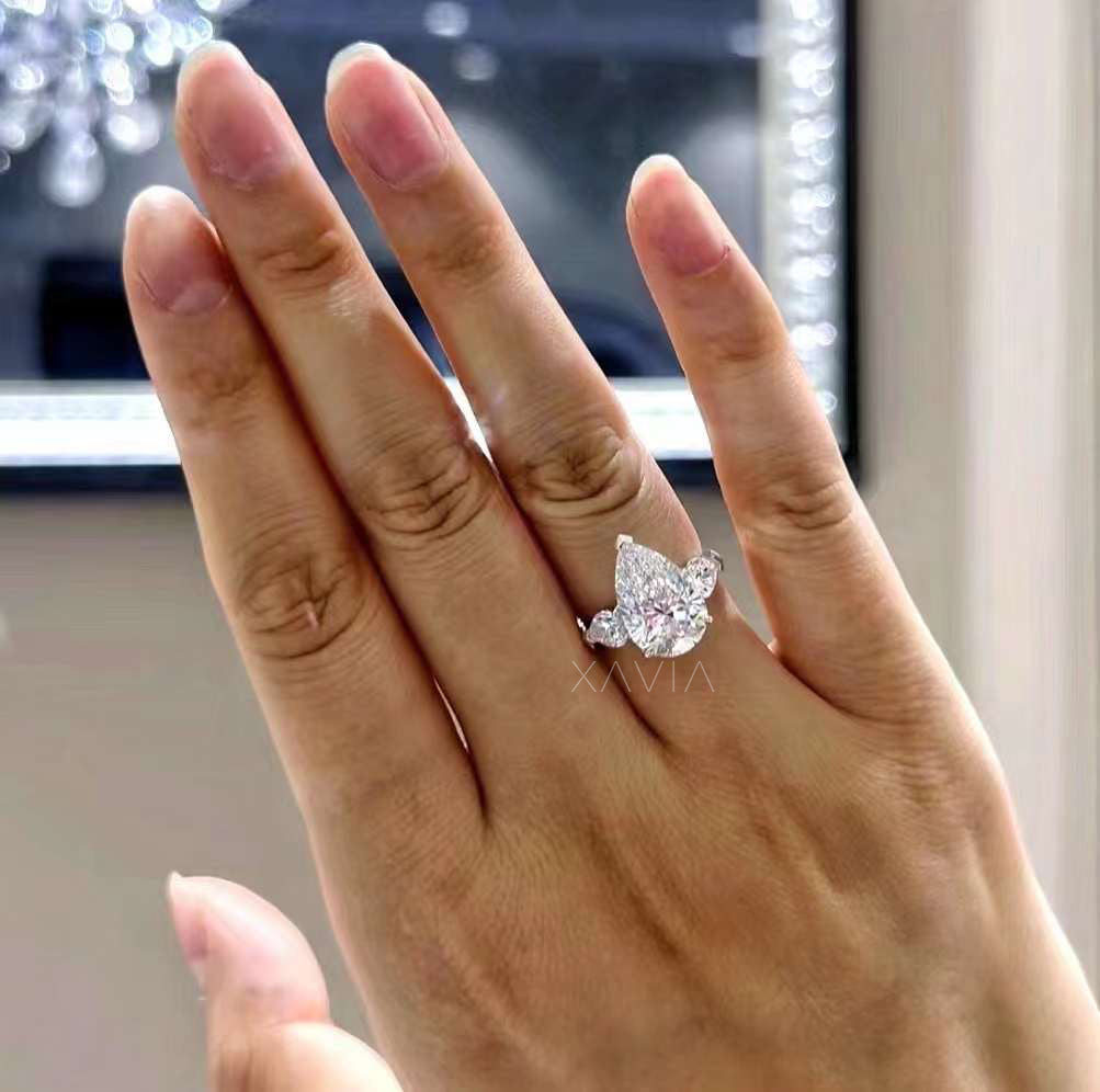 pear cut lab diamond three-stone engagement ring with tapered side stones worn on model’s hand, luxury bridal jewelry