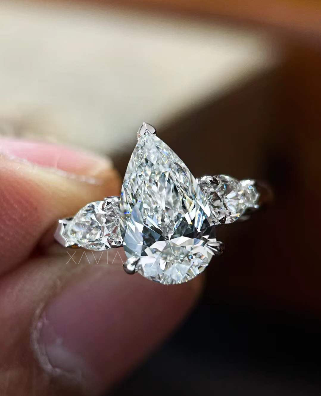 front angle of Novarae pear cut lab diamond engagement ring with two tapered side stones in classic prong setting