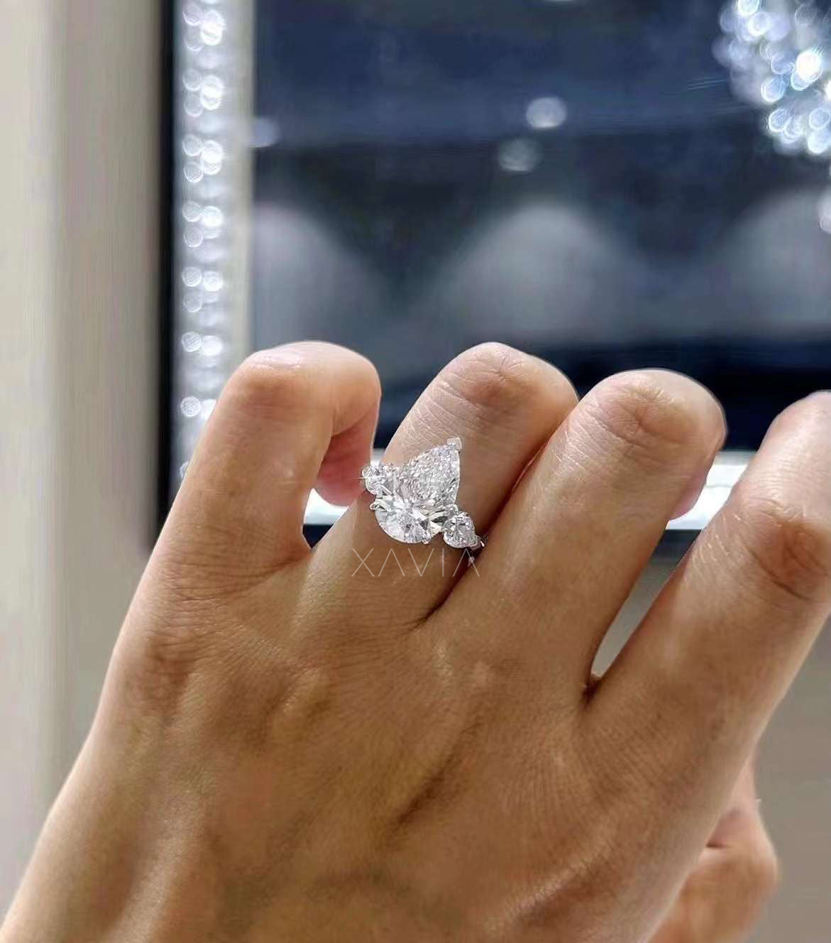 angled hand view of Novarae pear cut lab grown diamond engagement ring with tapered side stones and platinum band