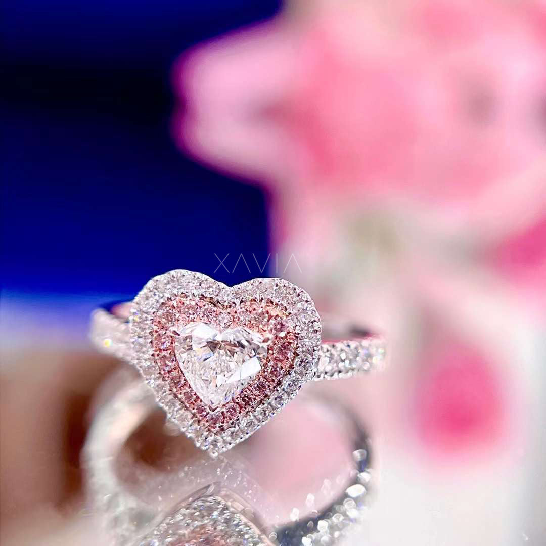 Elegant heart cut diamond engagement ring with blush pink pavé halo and brilliant white diamond accents, shown in floral background setting