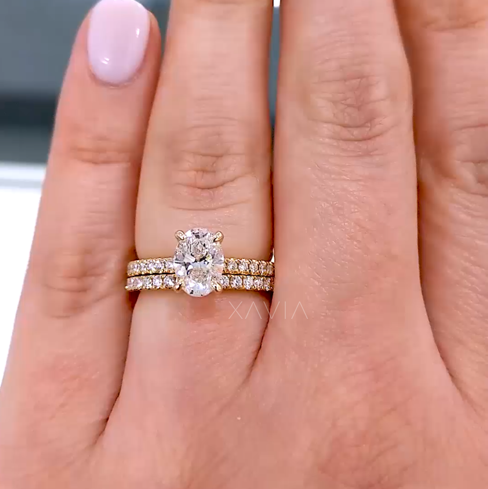 Oval-cut lab-grown diamond engagement ring in yellow gold on model’s hand, paired with pavé band