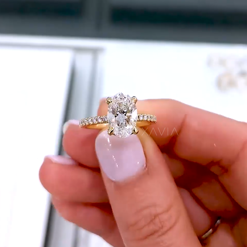 Close-up front view of oval-cut solitaire diamond ring held in hand