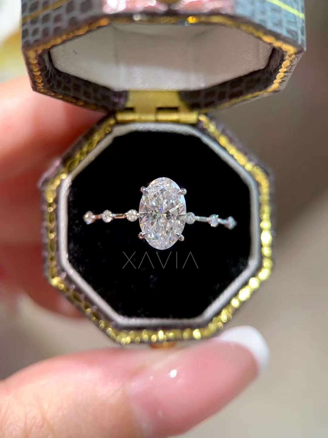 front view of oval cut lab diamond engagement ring with beaded side stones displayed in vintage style ring box
