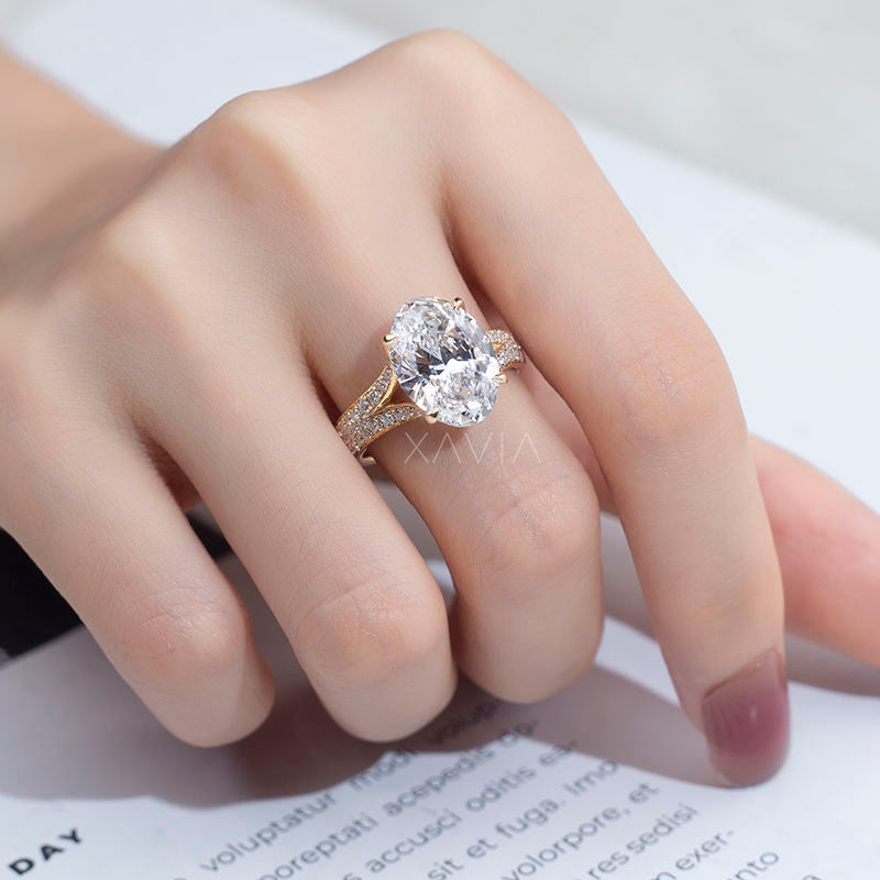 Close-up of oval cut lab grown diamond engagement ring in yellow gold worn on finger, showcasing pavé split shank band and elevated cathedral setting brilliance