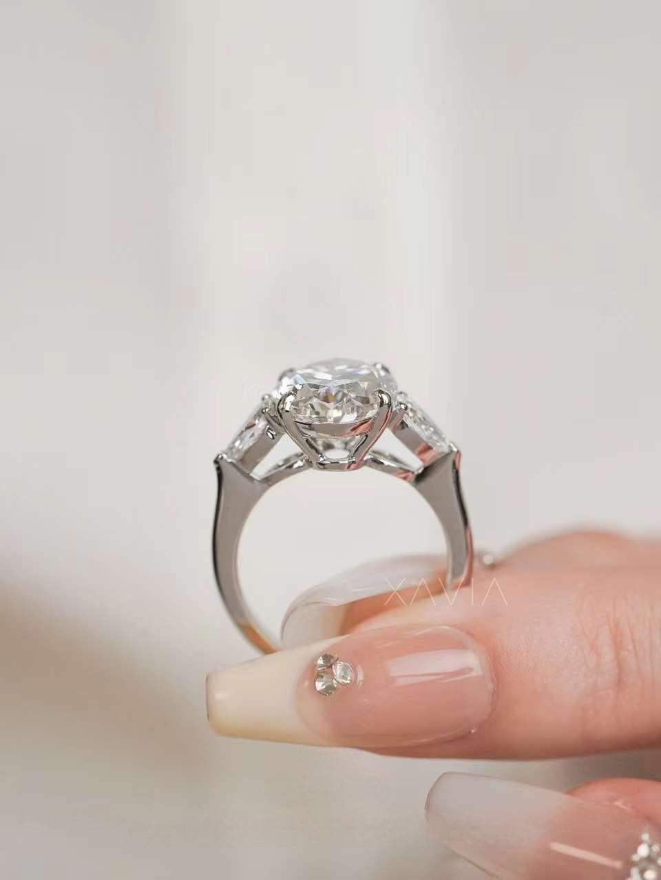 Lifestyle image of oval cut lab grown diamond engagement ring with marquise side stones styled on hand for scale and elegance