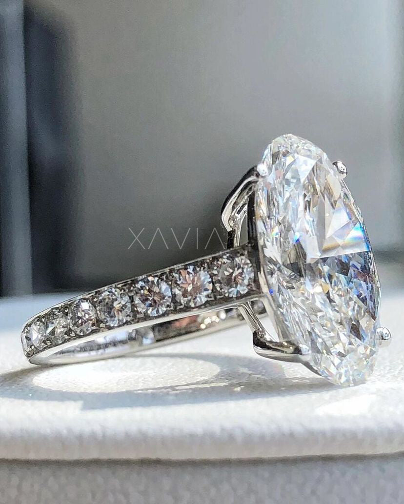 Large oval cut lab-grown diamond engagement ring with pavé side stones in platinum setting, worn on model’s hand in natural light