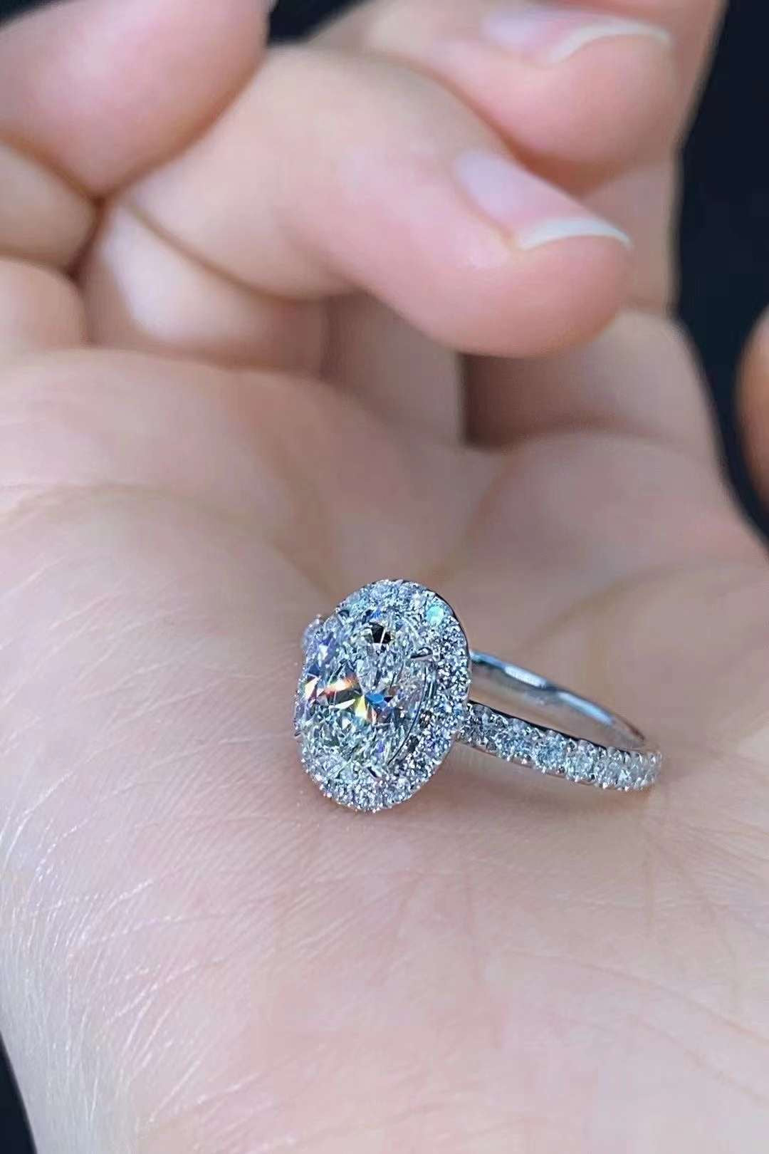 hand wearing oval lab diamond halo engagement ring with pavé band