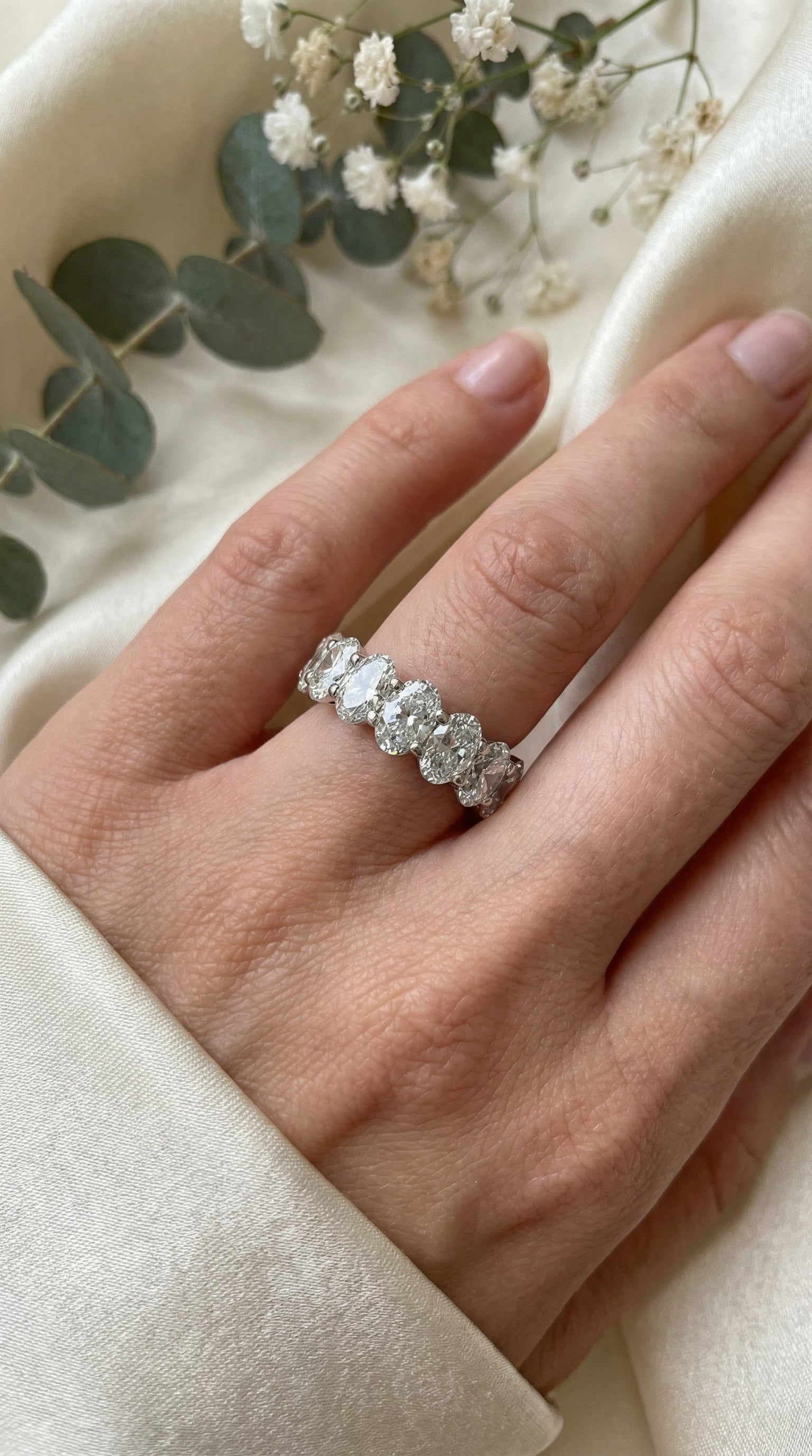 oval lab grown diamond eternity band ring displayed inside vintage velvet jewelry box with warm natural sunlight emphasizing diamond brilliance