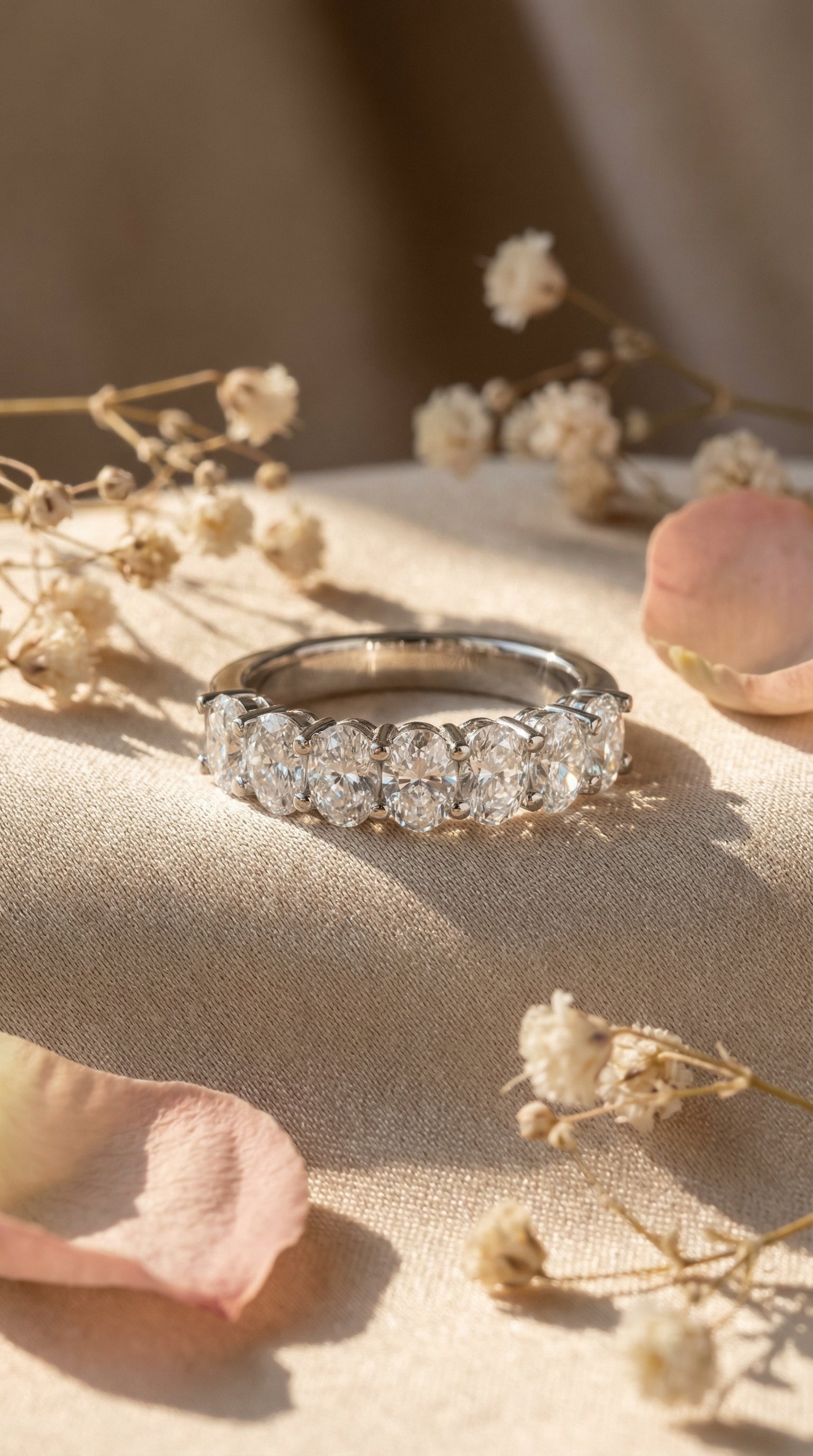 Oval cut lab grown diamond seven stone wedding band ring displayed on hand in soft natural light highlighting elongated diamond brilliance and modern bridal styling