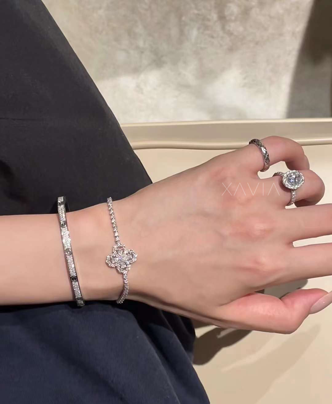 Close-up of oval halo diamond engagement ring in white gold worn on hand, paired with pavé diamond bracelet