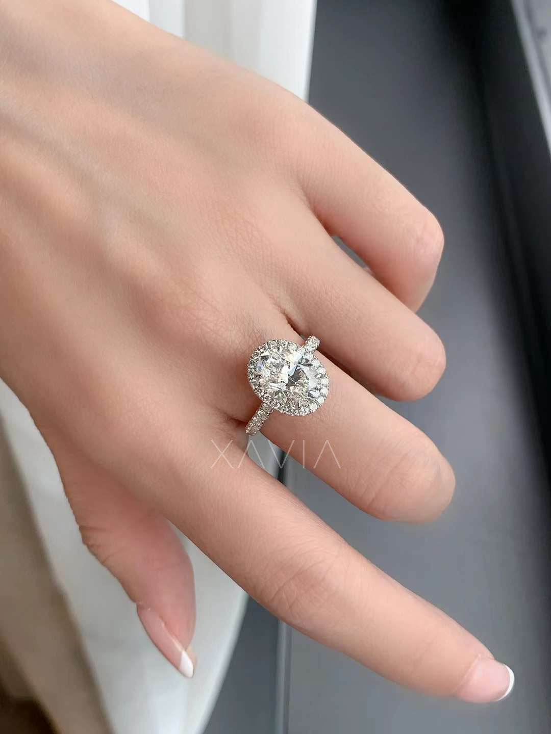 Handset oval cut halo engagement ring in luxury case, pavé shank details clearly visible on high-polish metal