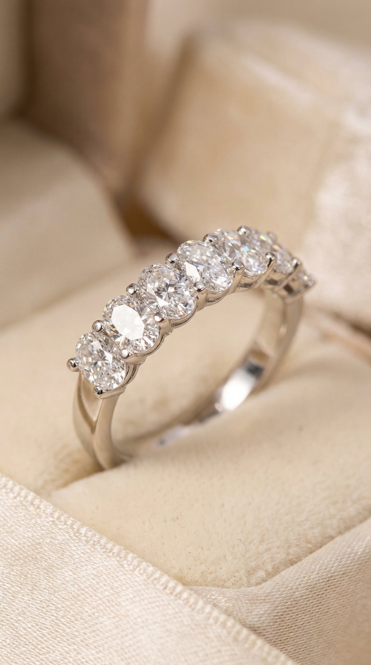 Three models wearing oval cut lab grown diamond seven stone bands demonstrating elegant stacking style and shared prong eternity band design