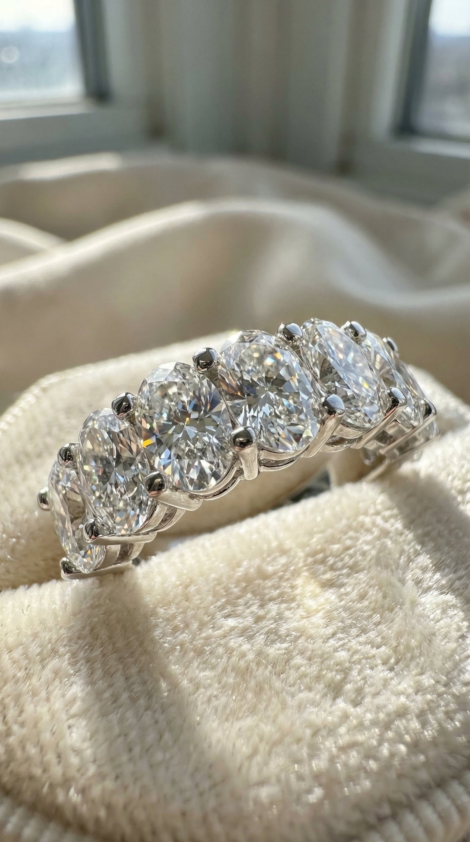 Side angle macro photograph of oval lab grown diamond half eternity band showing prong setting structure and diamond alignment across the ring