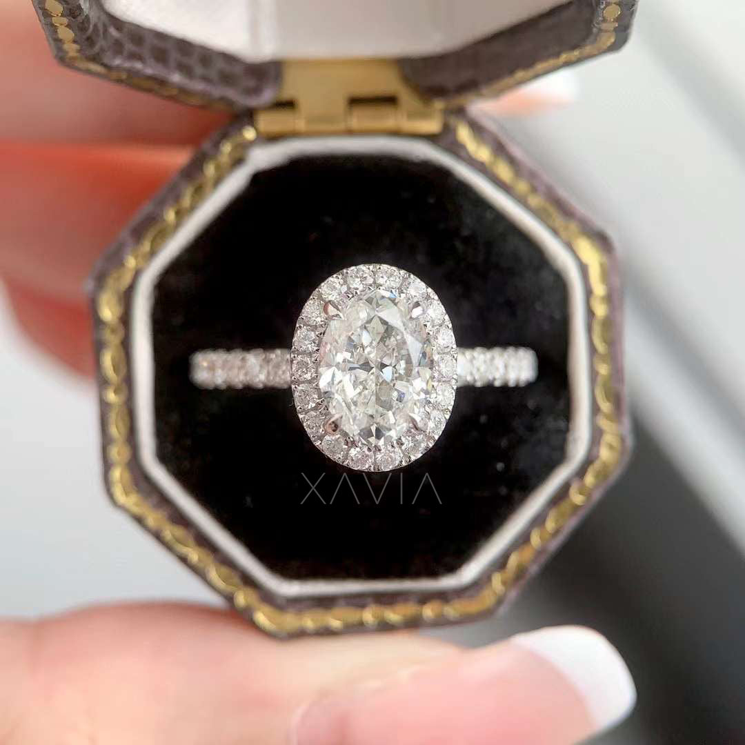 Top view of oval cut lab grown diamond halo engagement ring placed in luxury jewelry box highlighting oval center stone and round diamond halo brilliance