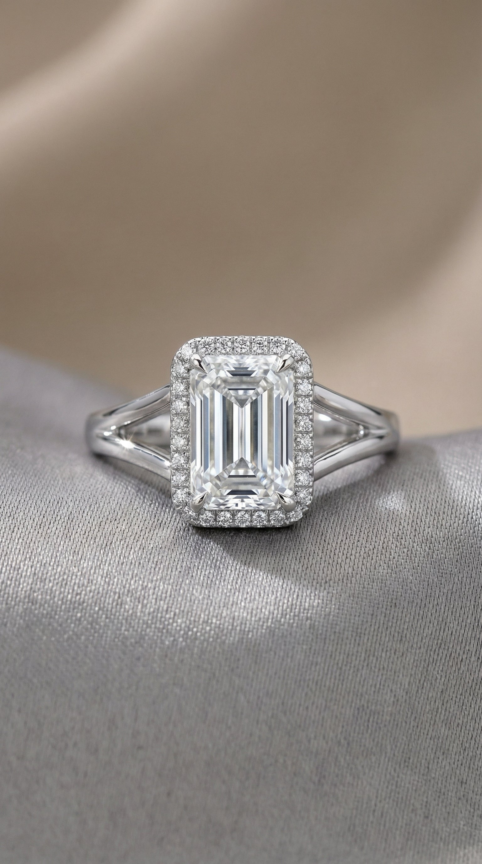 Diamond ring with emerald-cut center stone on a soft fabric background