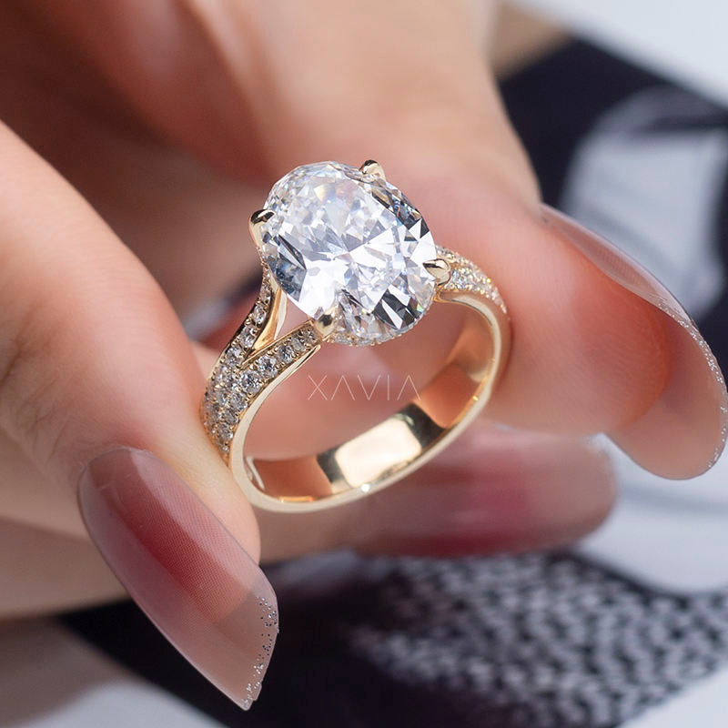 Luxury oval cut lab grown diamond engagement ring in yellow gold with pavé split shank band and cathedral setting, shown worn on a model hand displaying brilliant sparkle