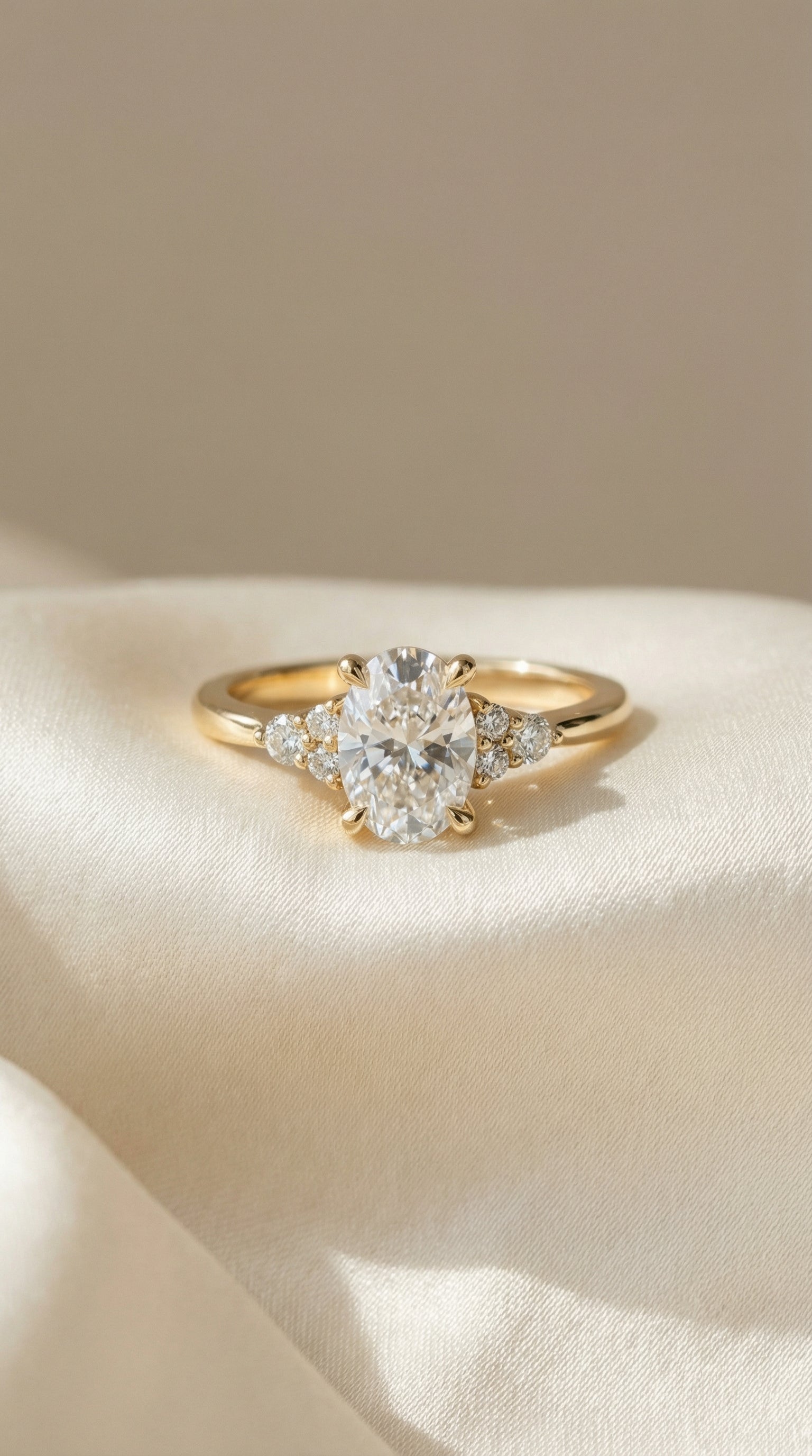 Oval cut lab-grown diamond engagement ring with round cluster side stones in a six-prong cathedral yellow gold setting.