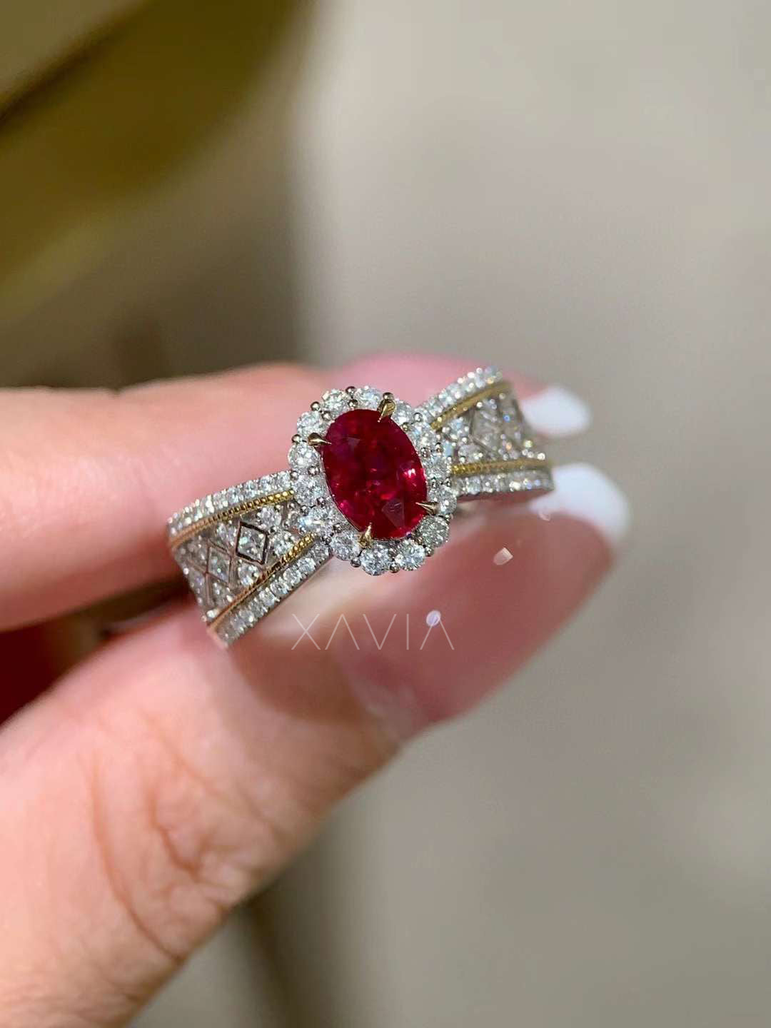 Angled macro view of oval red gemstone halo ring showing round diamond halo, split pavé diamond band and vintage lattice shoulder design crafted in high polish gold