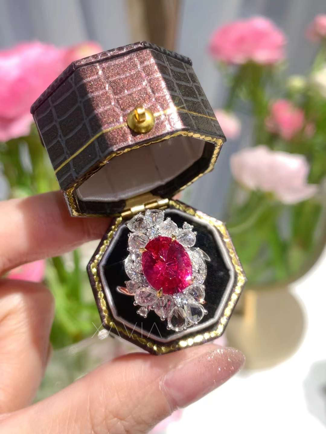 Oval ruby and diamond floral halo cocktail ring with marquise and pear diamonds displayed inside luxury jewelry box
